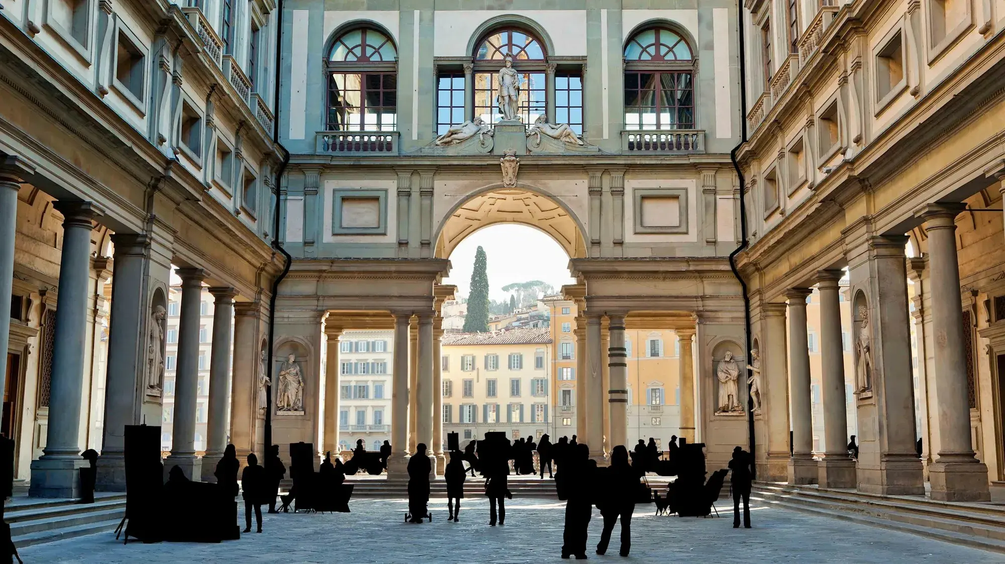The long courtyard of the Uffizi in Florence, framed by colonnades and opening onto the Arno