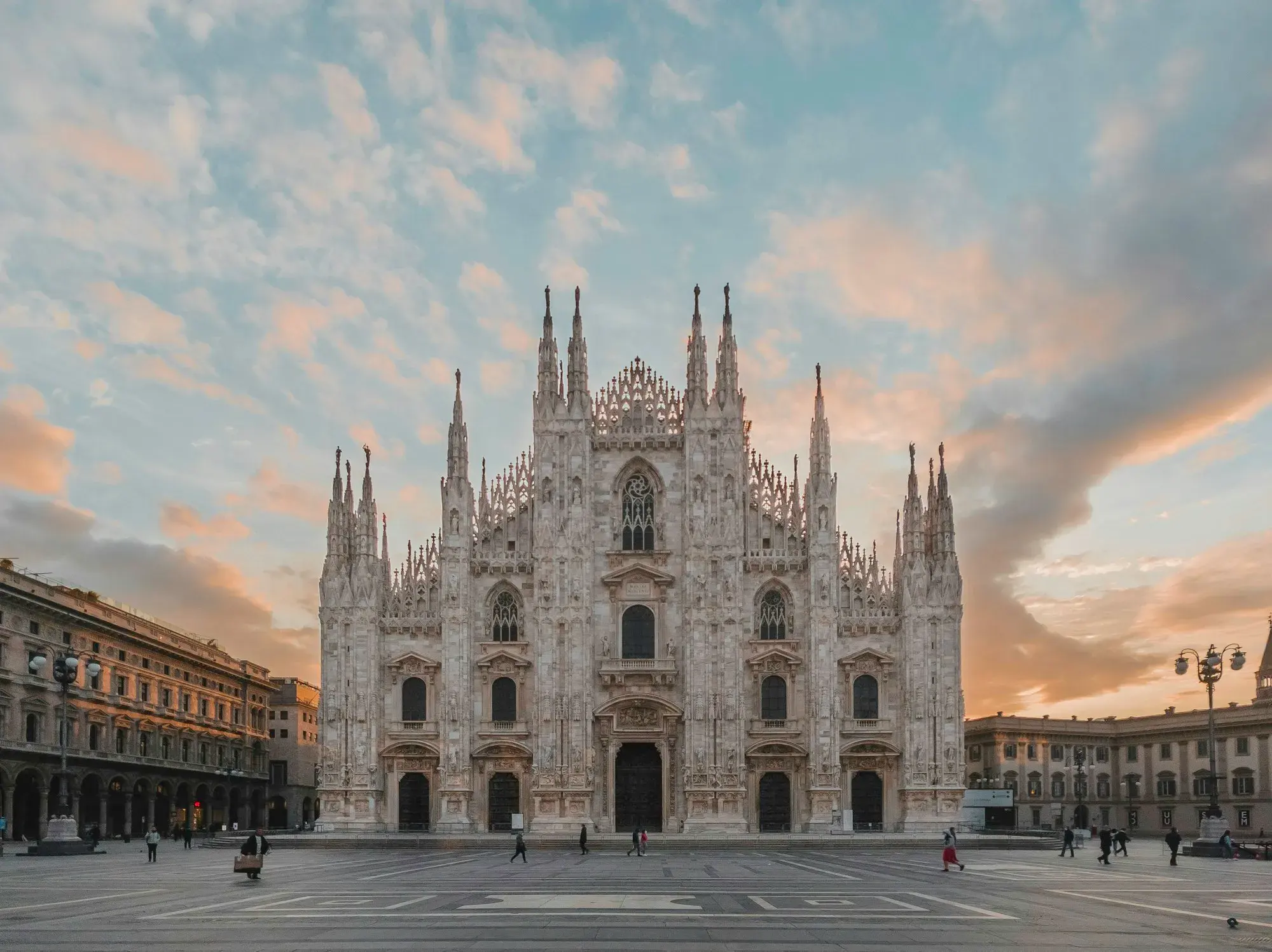 The white marble façade and spires of Milan Cathedral at dusk