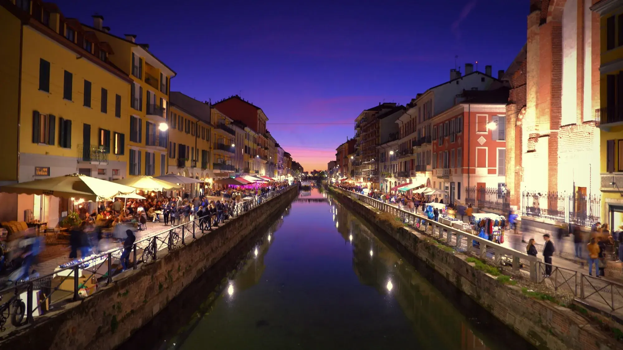 The Naviglio canal in Milan in the evening, lined with buildings and restaurant lights