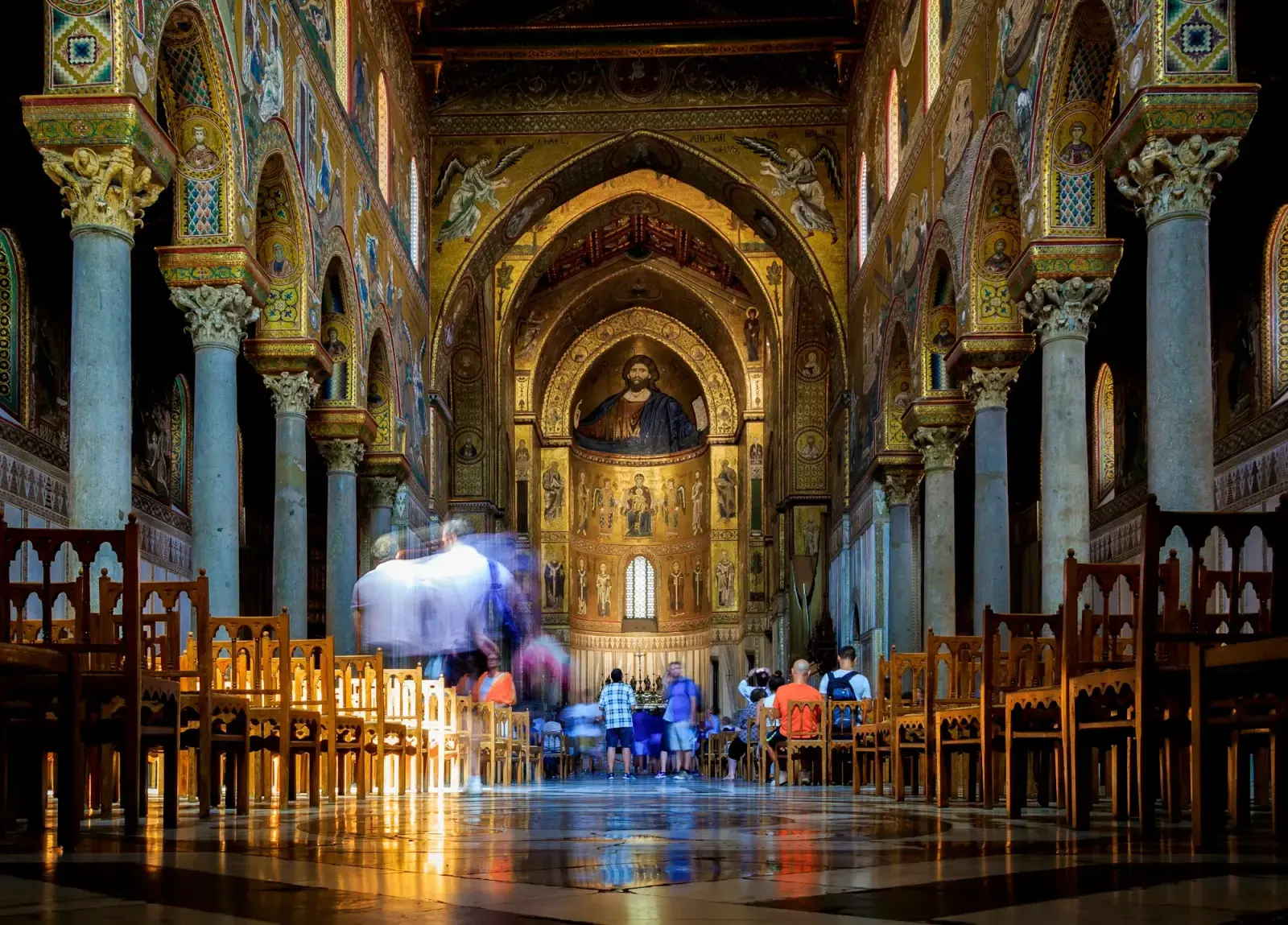 The nave of Monreale Cathedral, with walls and apse covered in gold mosaics and a large mosaic figure of Christ above the altar