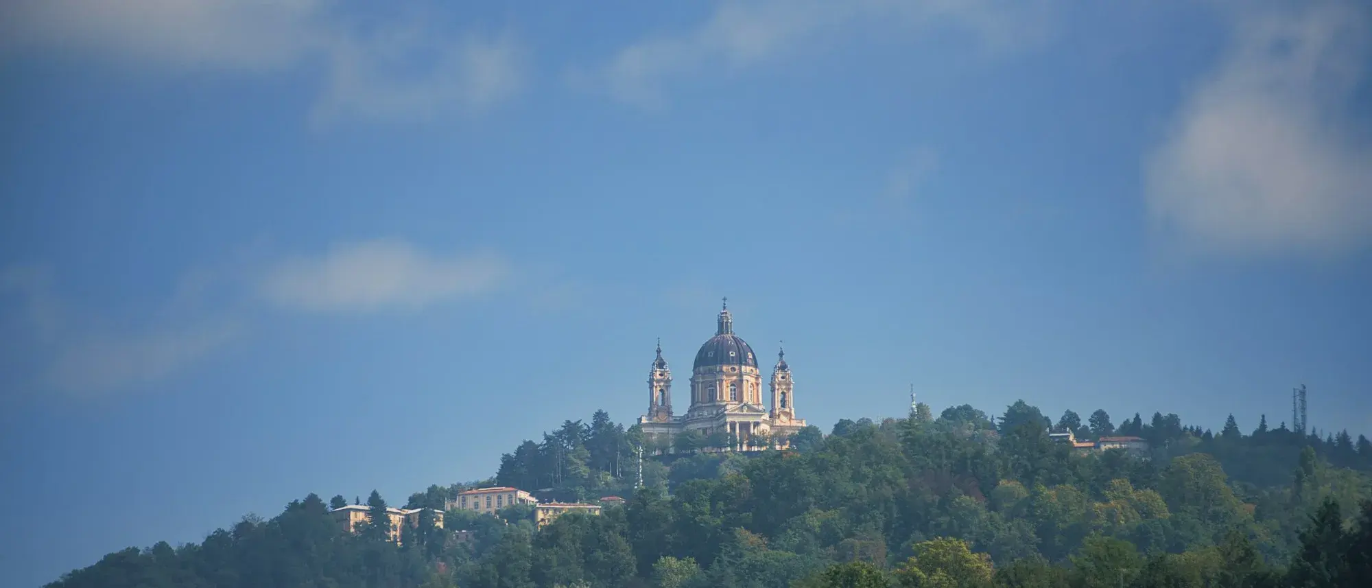 The Basilica of Superga with its dome and two bell towers on a wooded hilltop above Turin