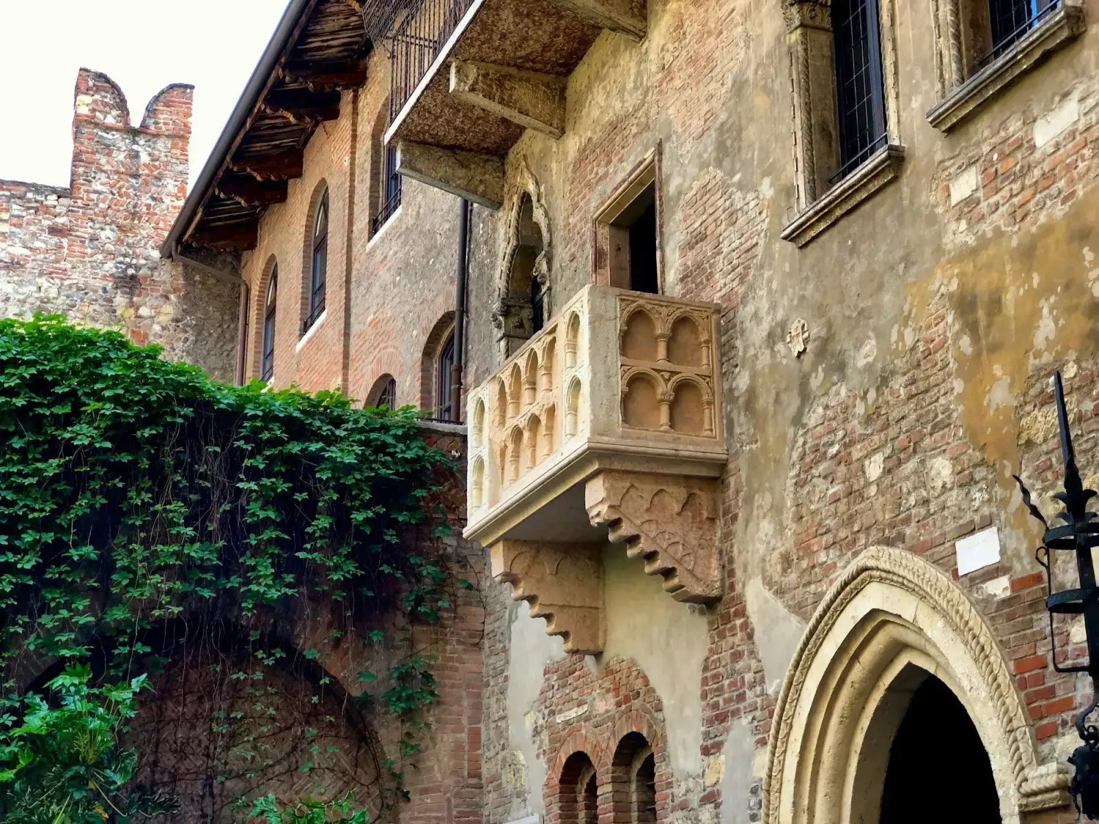 The stone balcony on the brick façade of Casa di Giulietta in Verona, with ivy on the courtyard wall