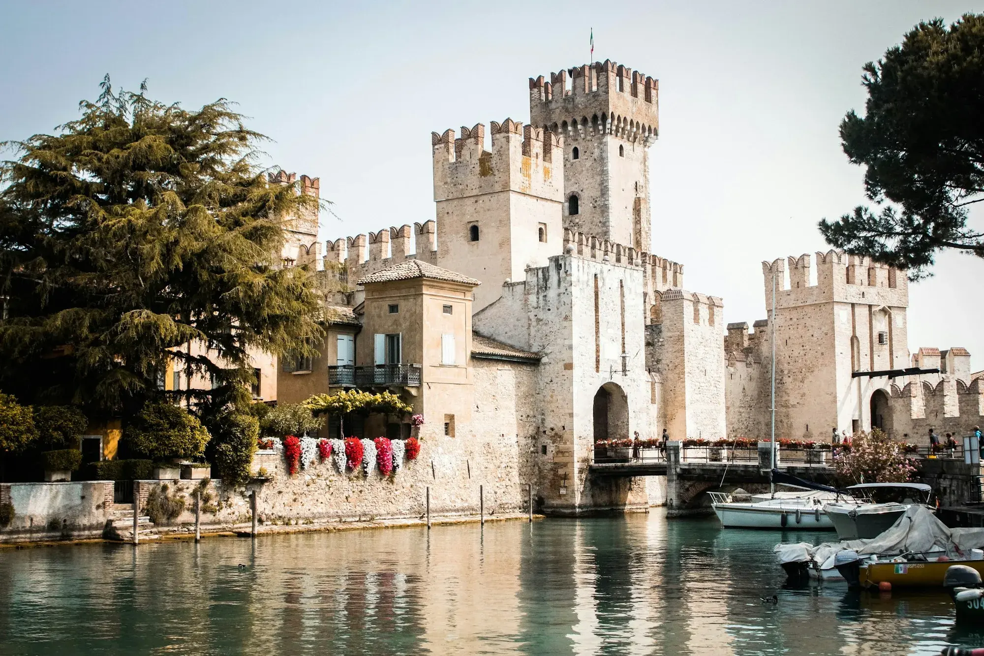 The Scaliger castle at Sirmione on Lake Garda, with crenellated towers rising from the water and boats moored in front