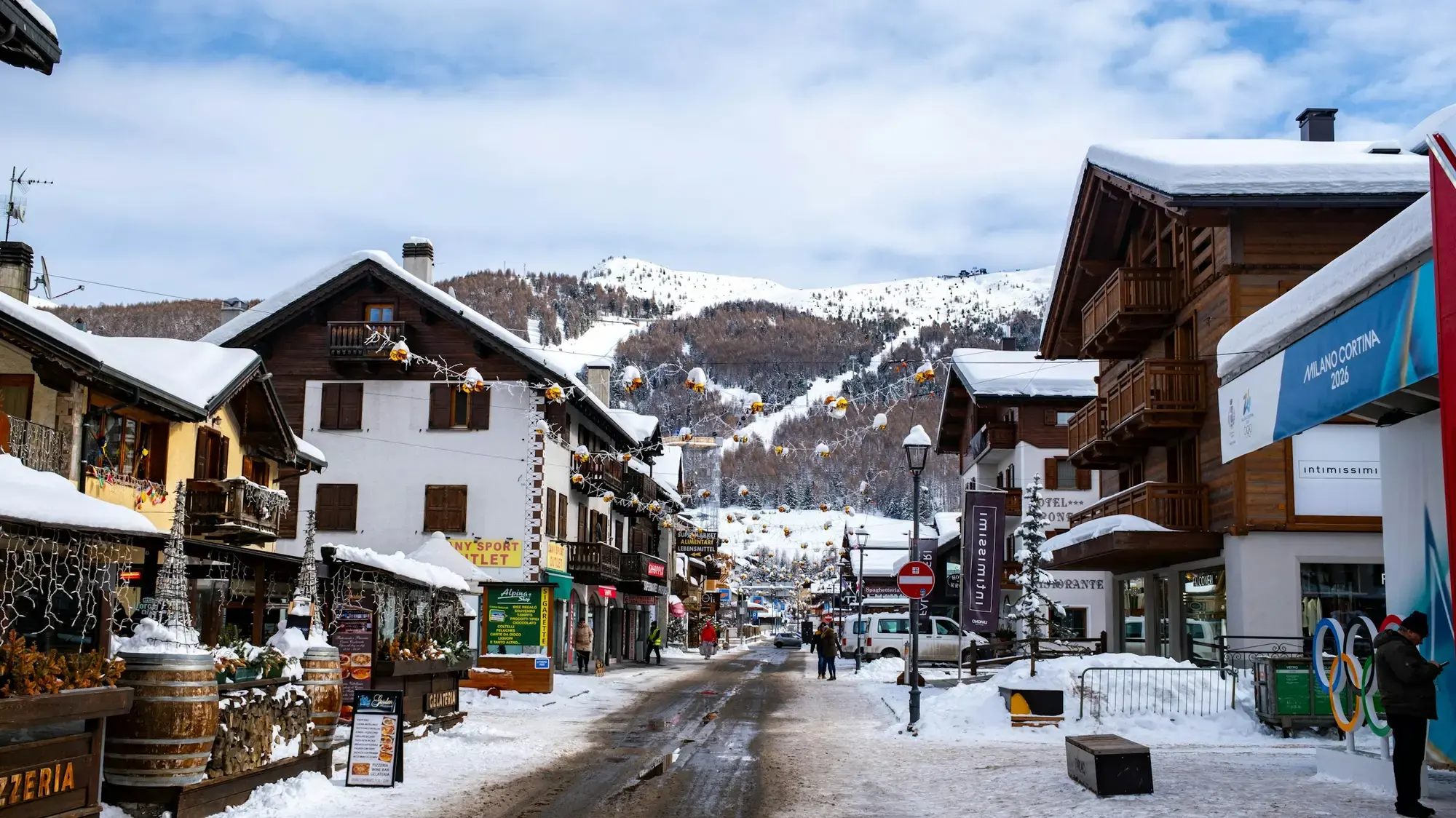 Una strada innevata in un paese alpino di montagna, con edifici tradizionali in pietra e legno