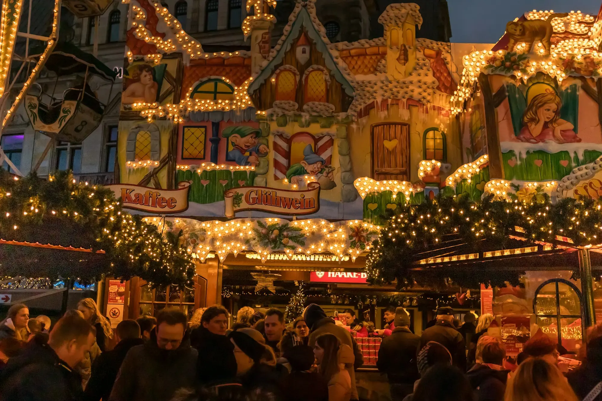Una folla di visitatori a un mercatino natalizio notturno con le bancarelle illuminate