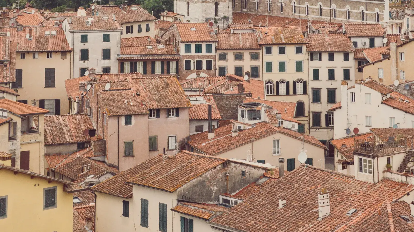 Stone bell towers rising above a terracotta rooftop panorama in Lucca's historic centre