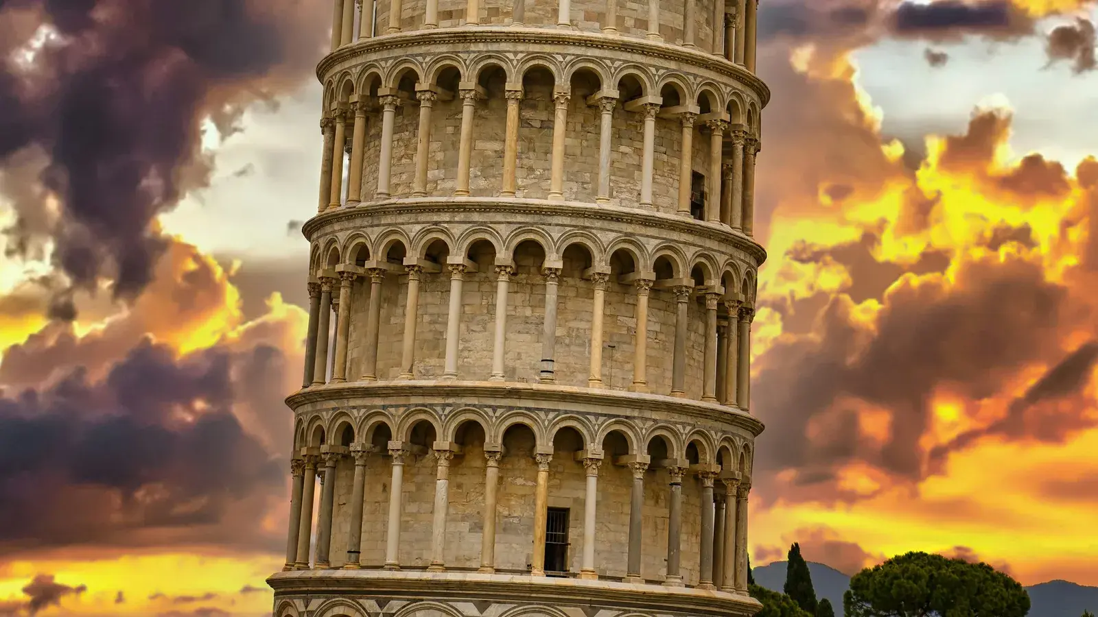 The Leaning Tower of Pisa rising from the green lawn of Piazza dei Miracoli under a blue sky