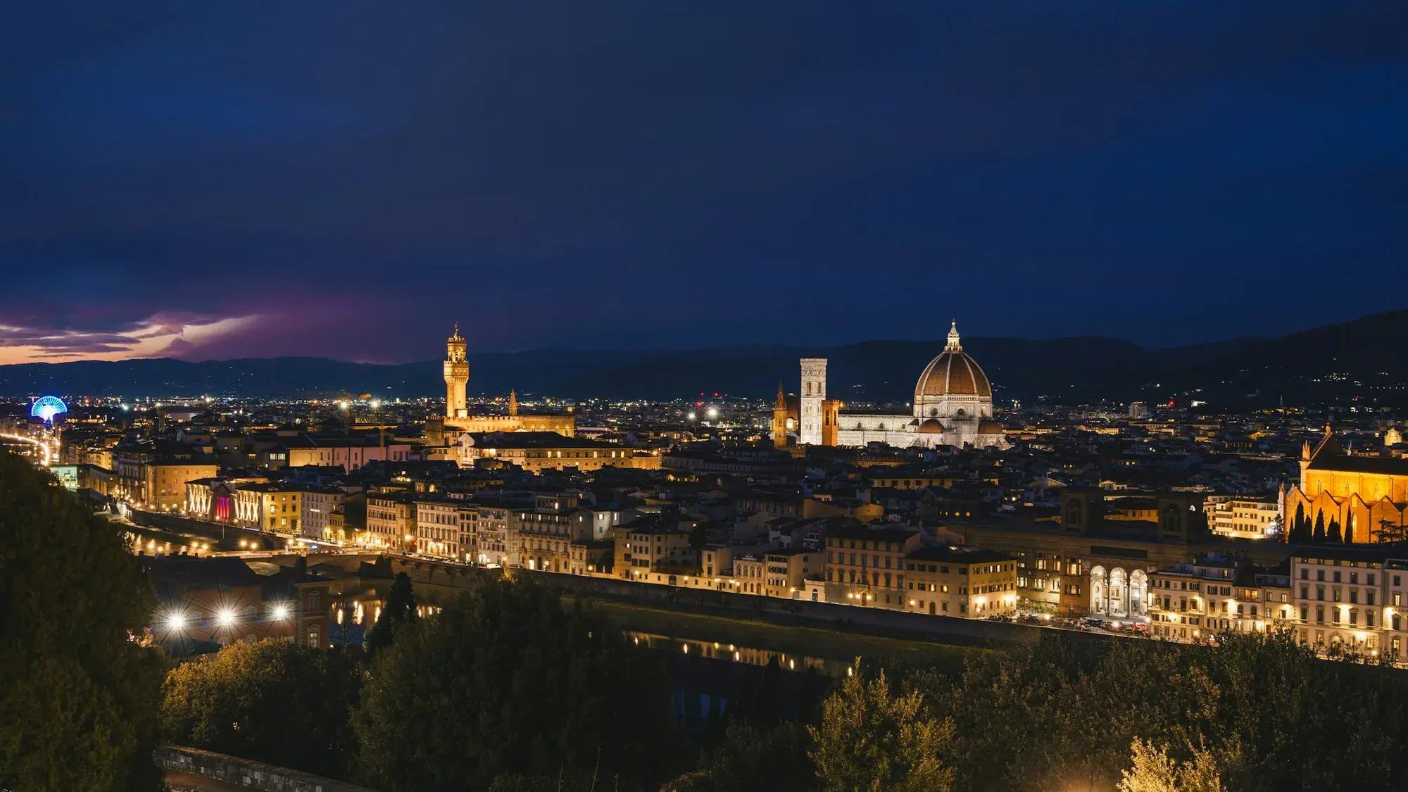 Lo skyline illuminato di Firenze di notte, con la cupola del Duomo e la torre di Palazzo Vecchio che si stagliano sopra la città