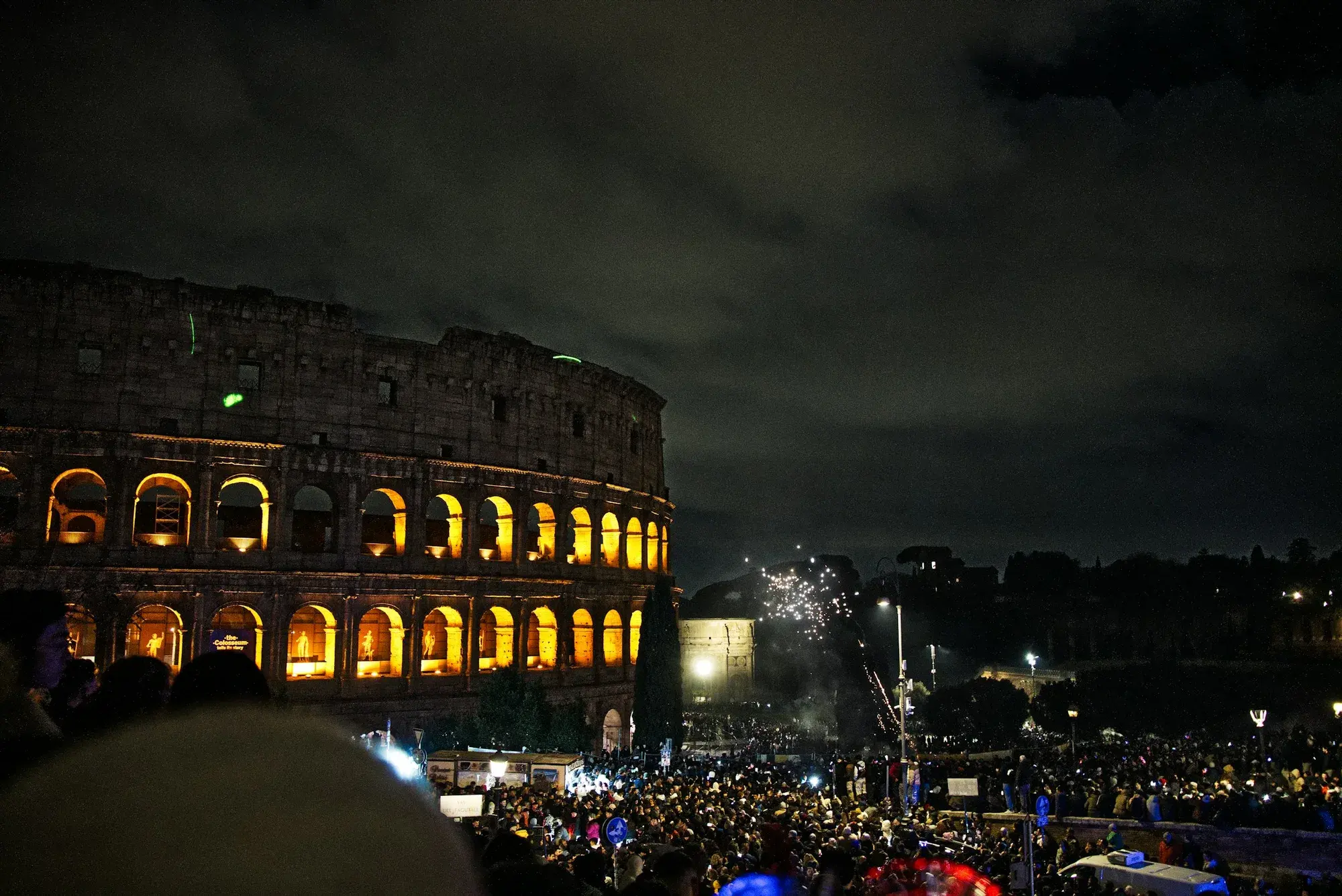 Il Colosseo illuminato di notte con una folla riunita ai piedi dell'anfiteatro