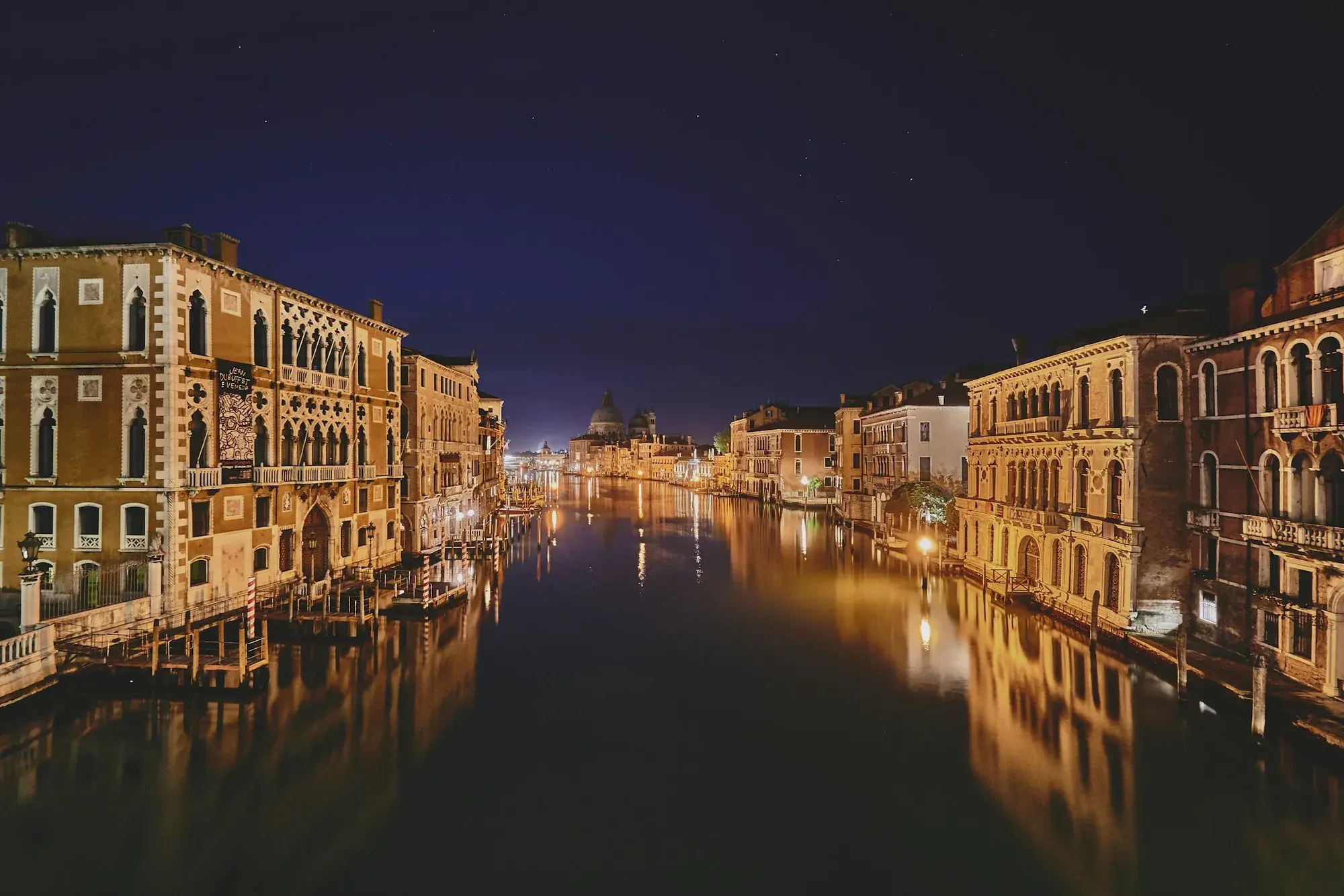 Edifici illuminati e i loro riflessi in un canale veneziano in una calma notte invernale