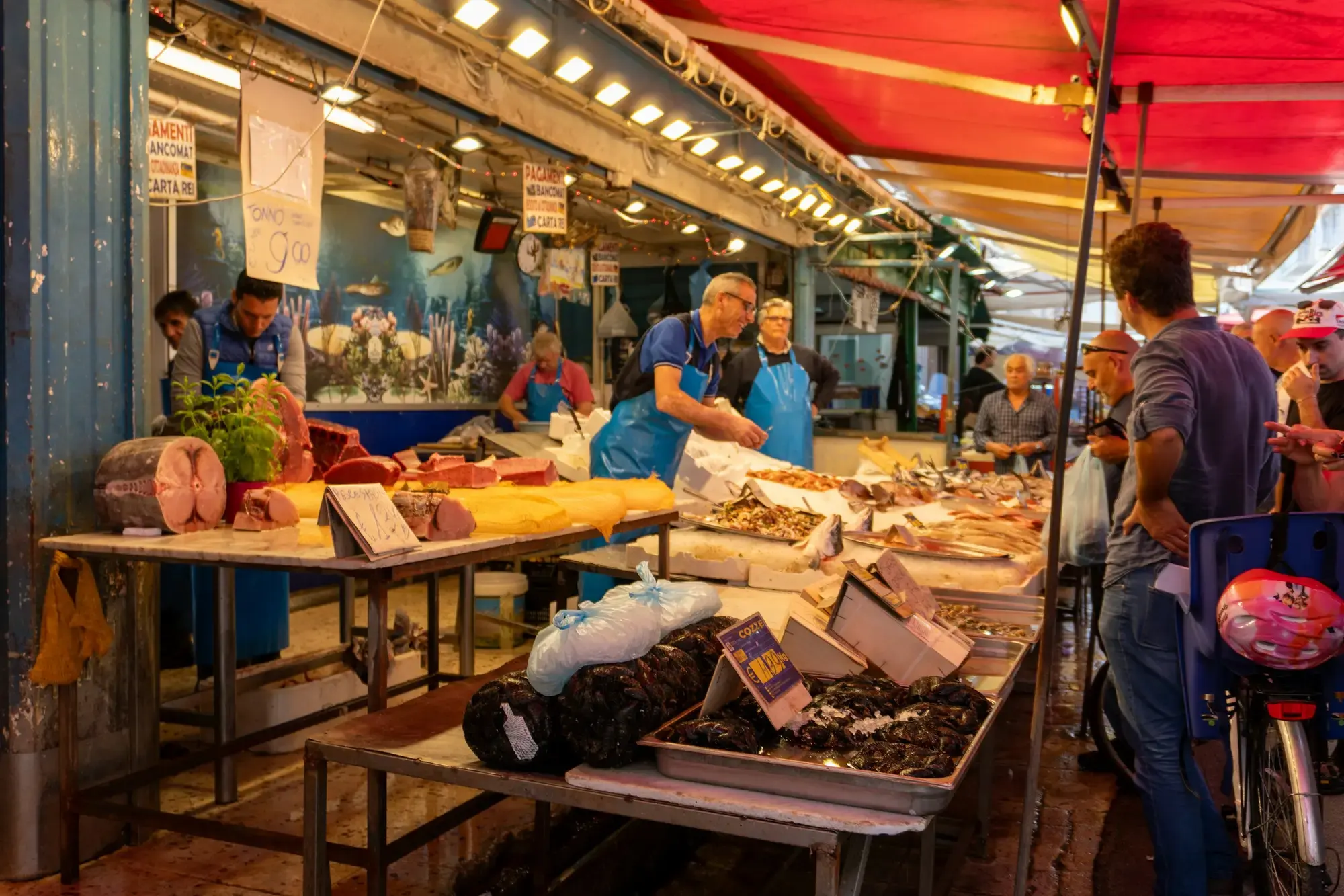 Clienti e venditori a un affollato banco di mercato ittico e alimentare