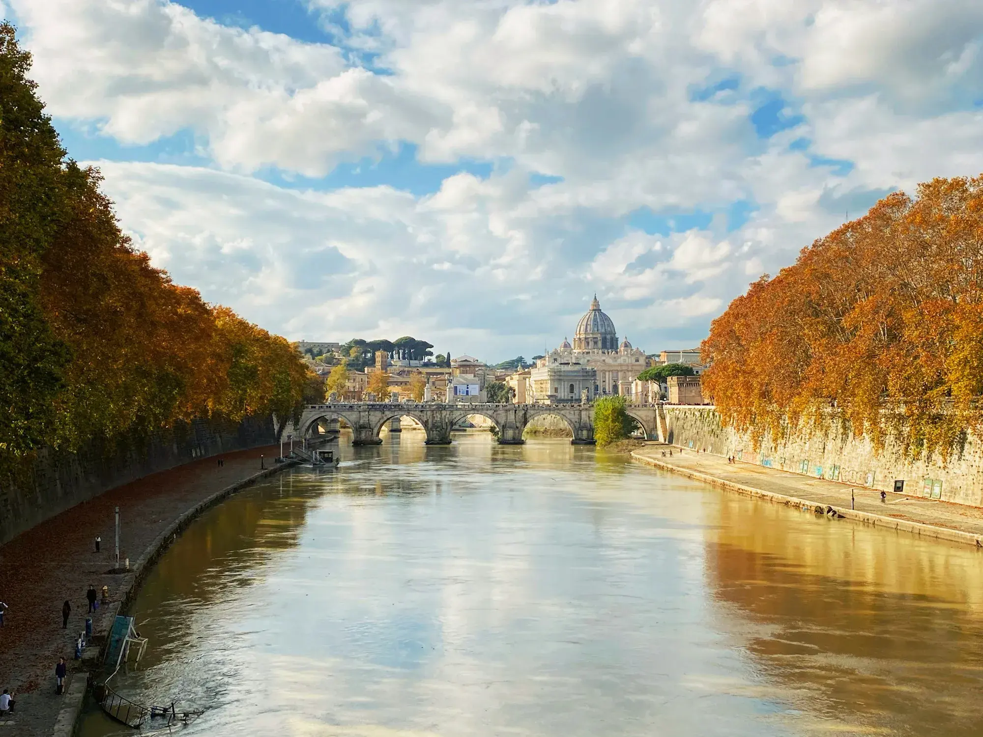 Autumn trees along the Tiber in Rome, with the dome of St Peter's Basilica in the distance