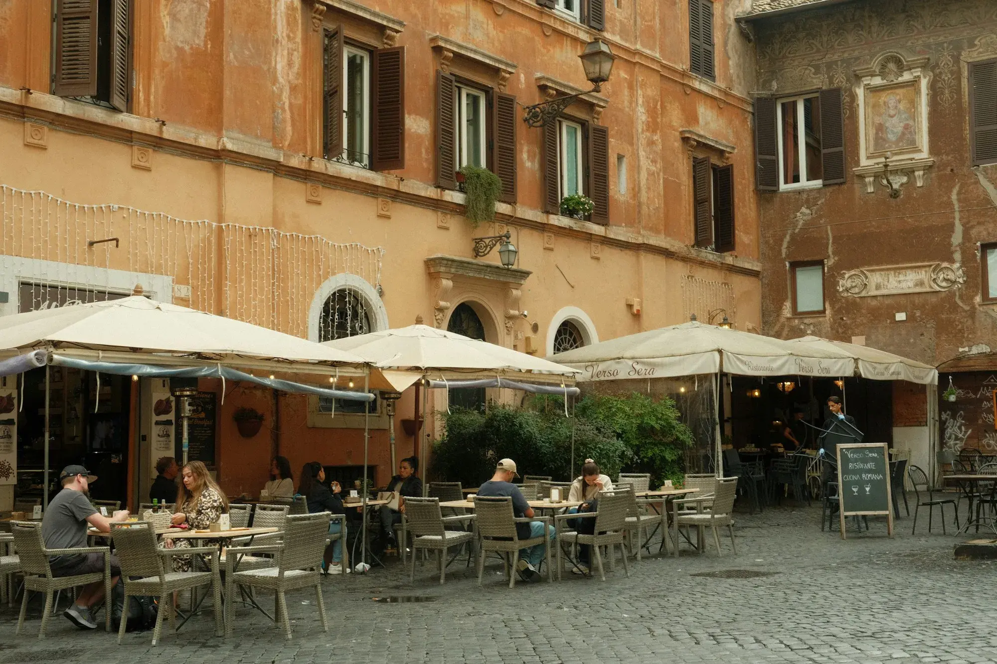 Tavoli di un ristorante all'aperto accanto a un edificio in una via di Roma