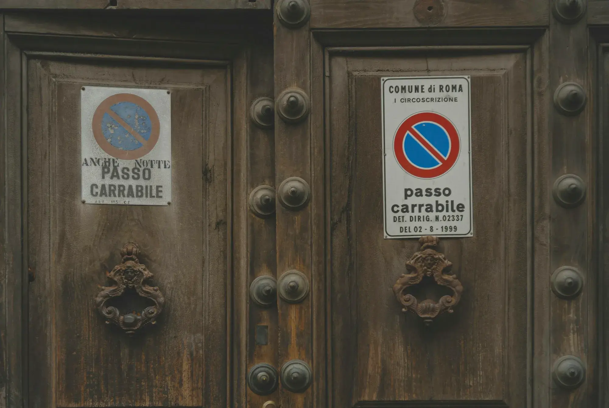 A "passo carrabile" no-parking sign on a large wooden door in Rome