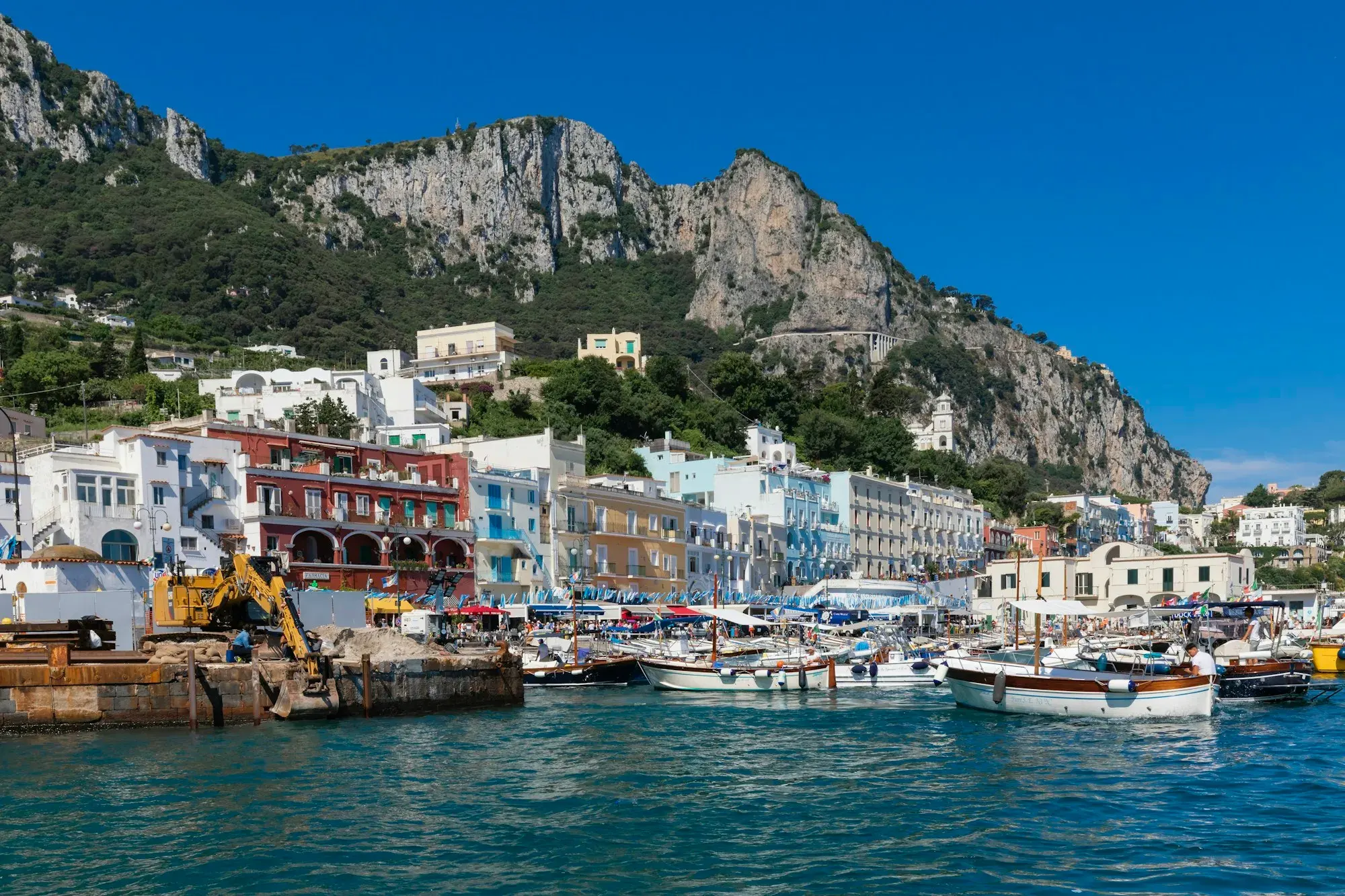 The harbour of Marina Grande on Capri, with boats, colourful buildings and steep limestone cliffs above