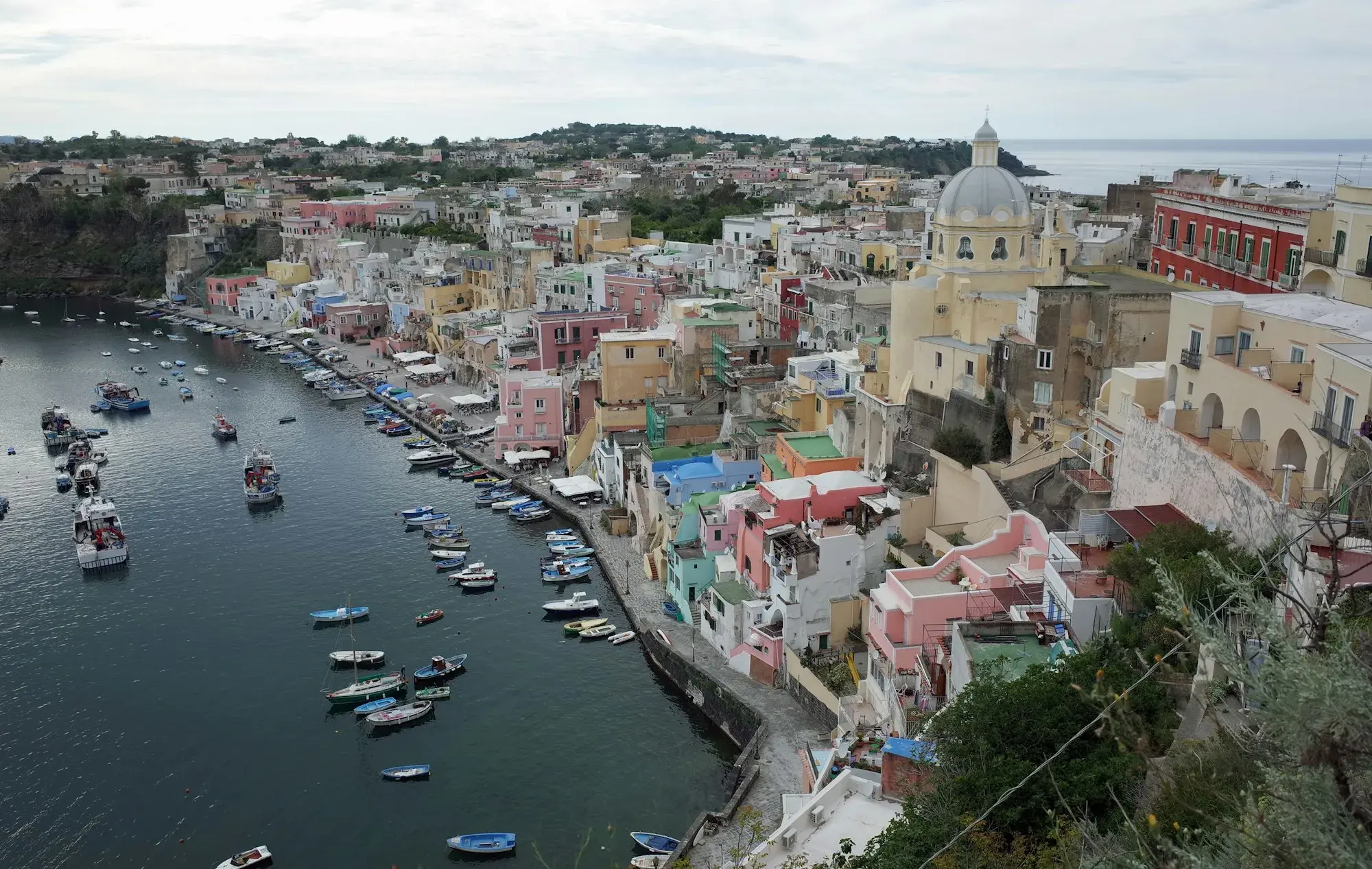 The colourful houses of Corricella on Procida curving around a small harbour full of boats