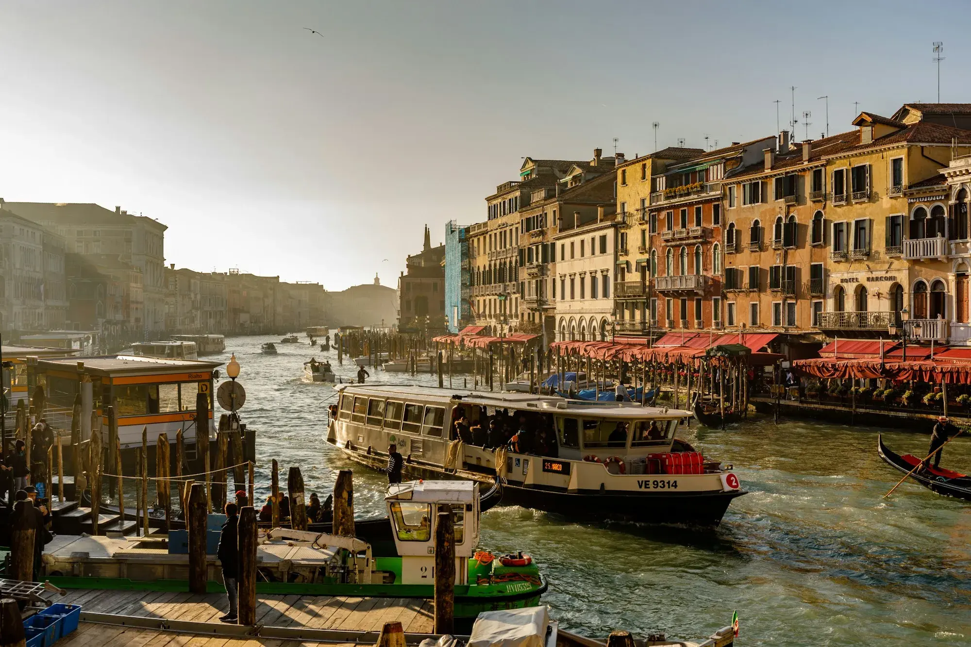 A vaporetto water bus on the Grand Canal in Venice, passing a floating stop and canal-side buildings