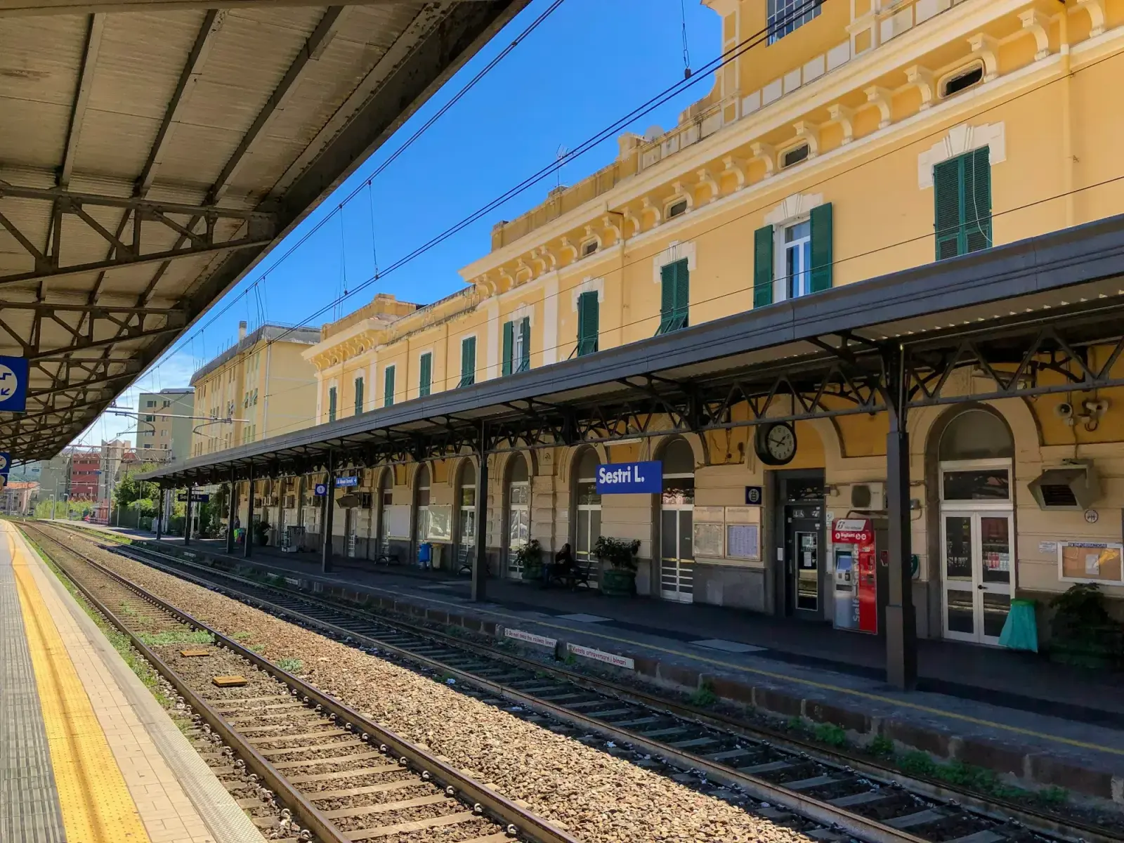 The yellow station building and platform at Sestri Levante in Liguria, with railway tracks under a blue sky