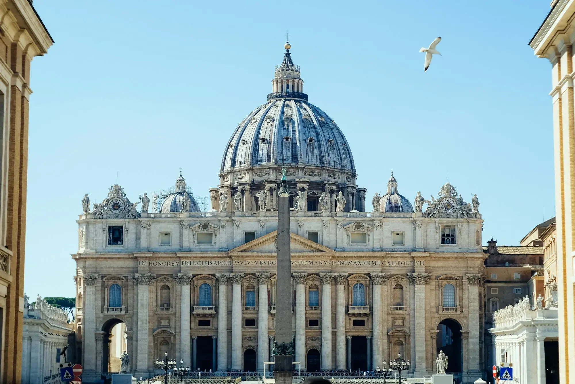 The façade and dome of St Peter's Basilica in the Vatican under a clear blue sky
