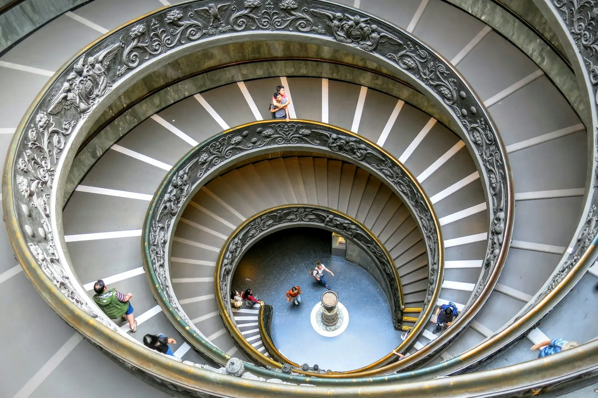 The double spiral staircase at the Vatican Museums seen from above, with visitors walking down its curving ramps