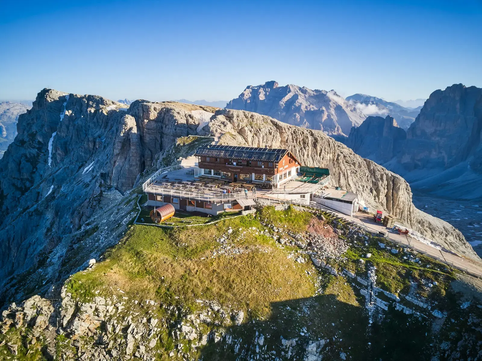 Rifugio Lagazuoi, a large wooden-clad mountain hut on a rocky summit, surrounded by grey peaks