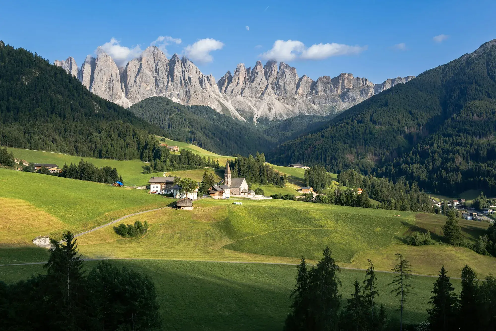 The village and church of Santa Maddalena in green meadows, below the jagged grey Odle peaks in Val di Funes