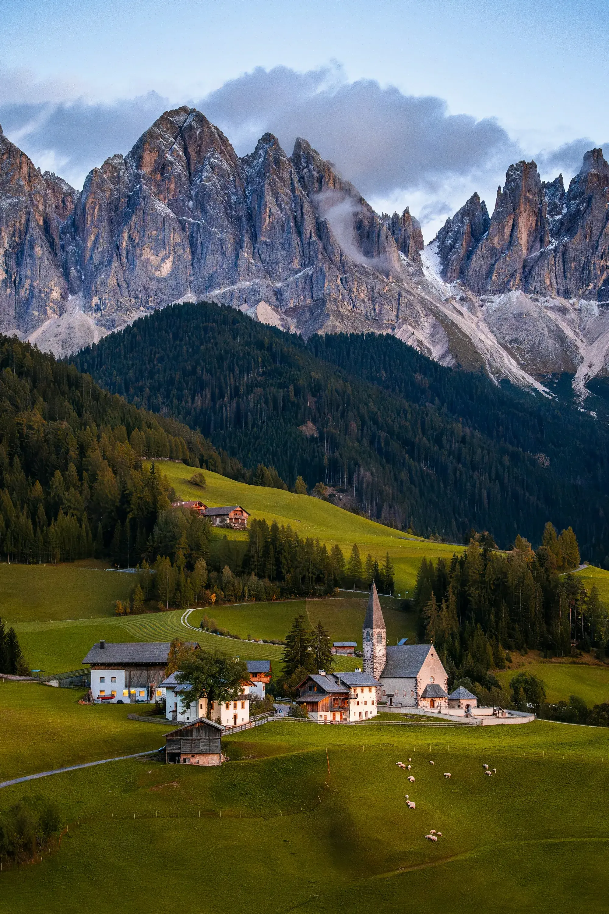 A traditional alpine village in South Tyrol surrounded by amber autumn-coloured trees and snow-dusted peaks