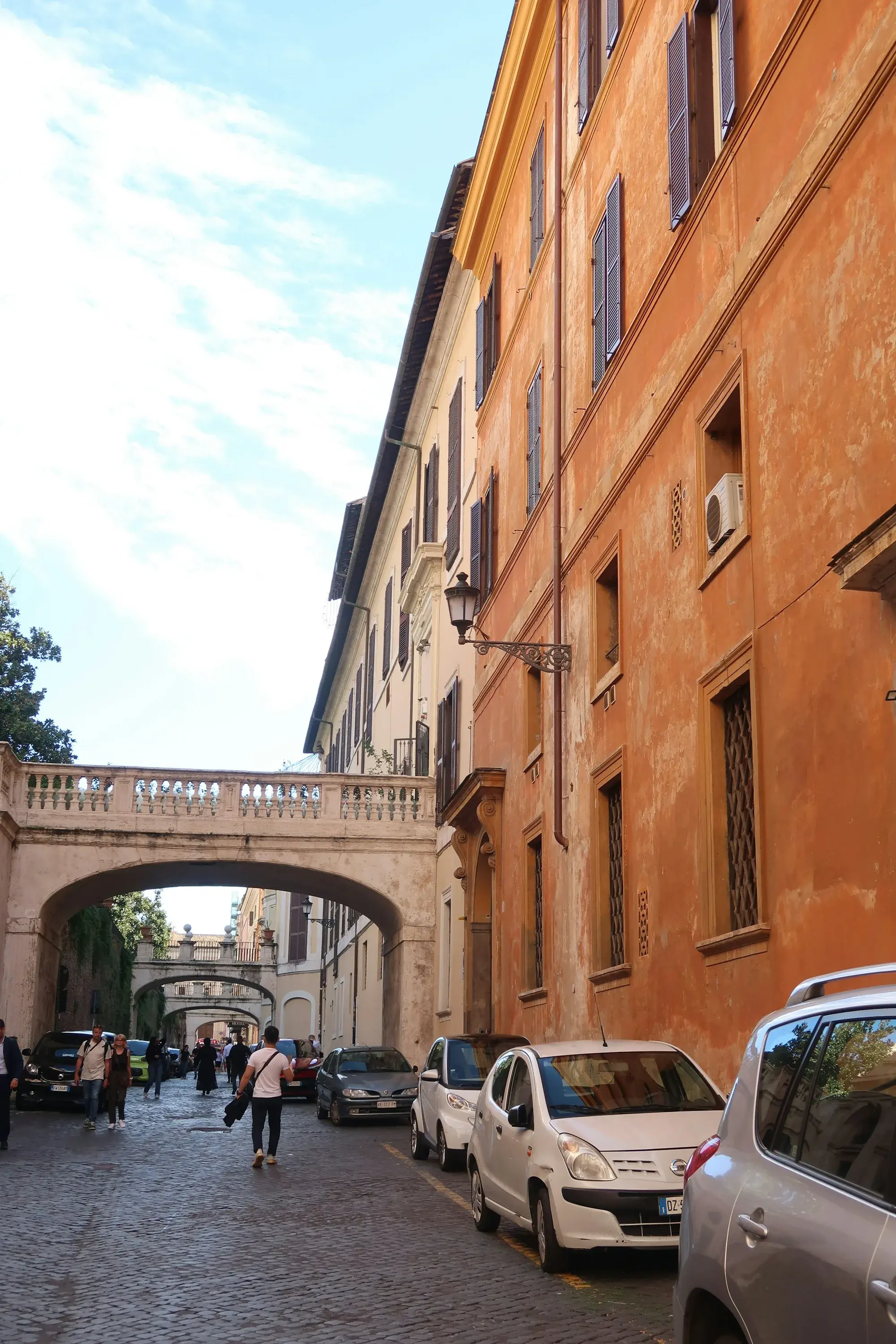 A quiet Rome street with an arched bridge reflected in the Tiber on a grey November morning