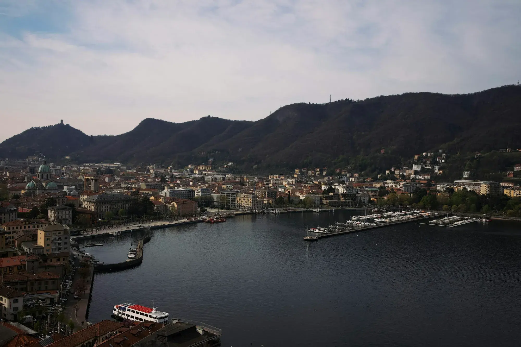 The city of Como at dusk, with lights along the shore and mountains around the lake