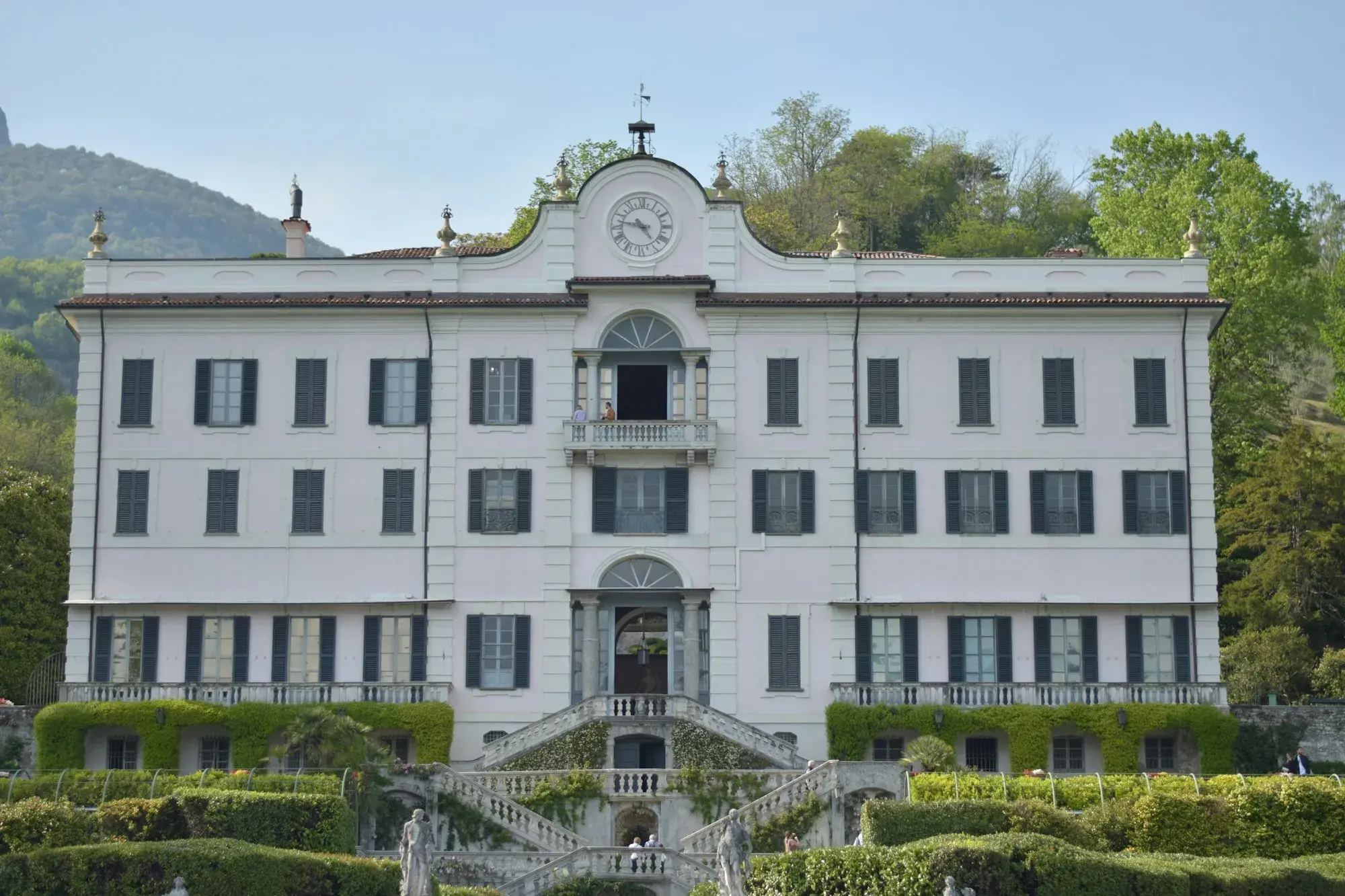 The white façade of Villa Carlotta in Tremezzo with a fountain and formal garden in front