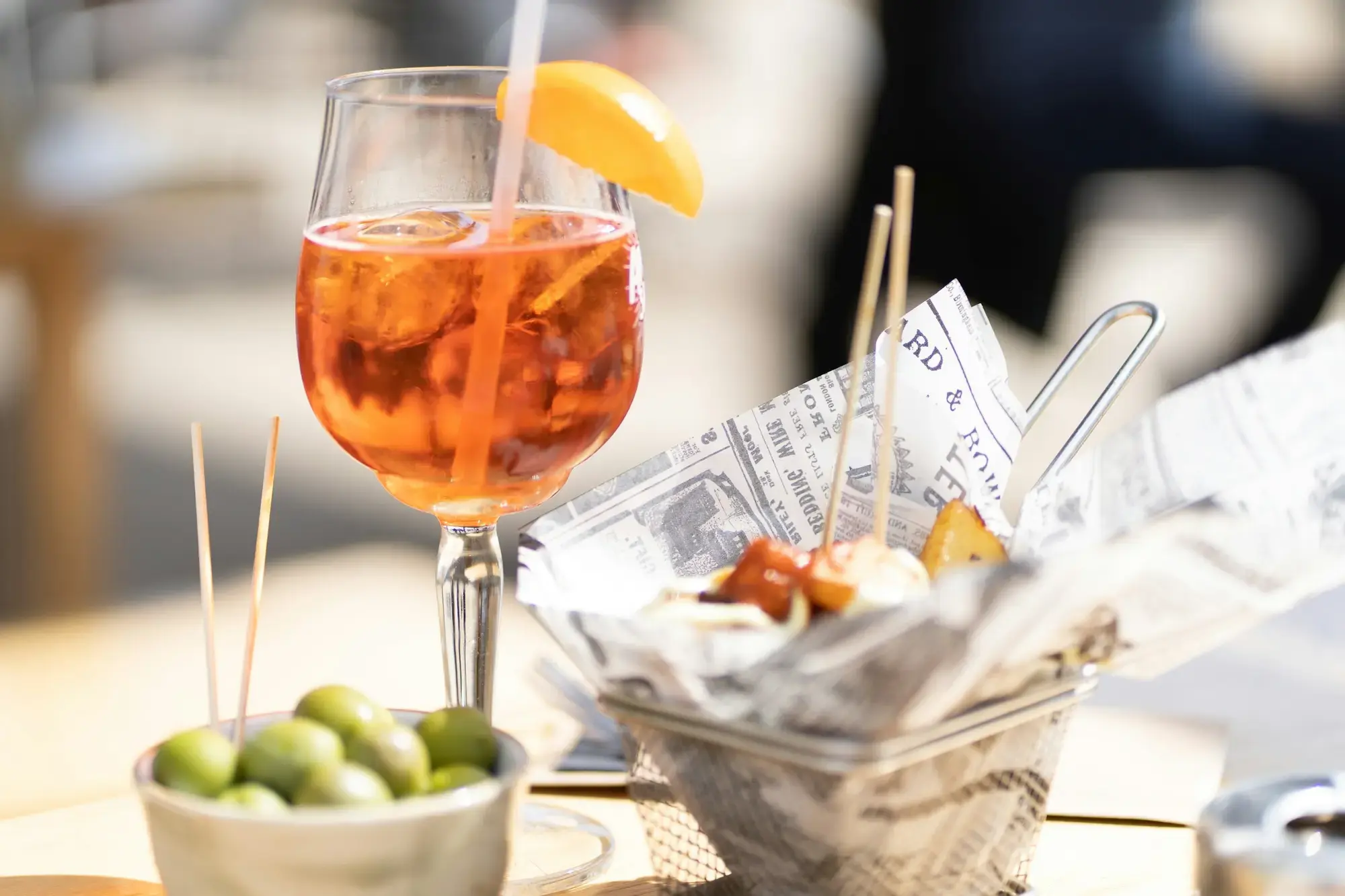 A glass of bright orange aperitivo drink — possibly an Aperol Spritz — on a table at an Italian bar