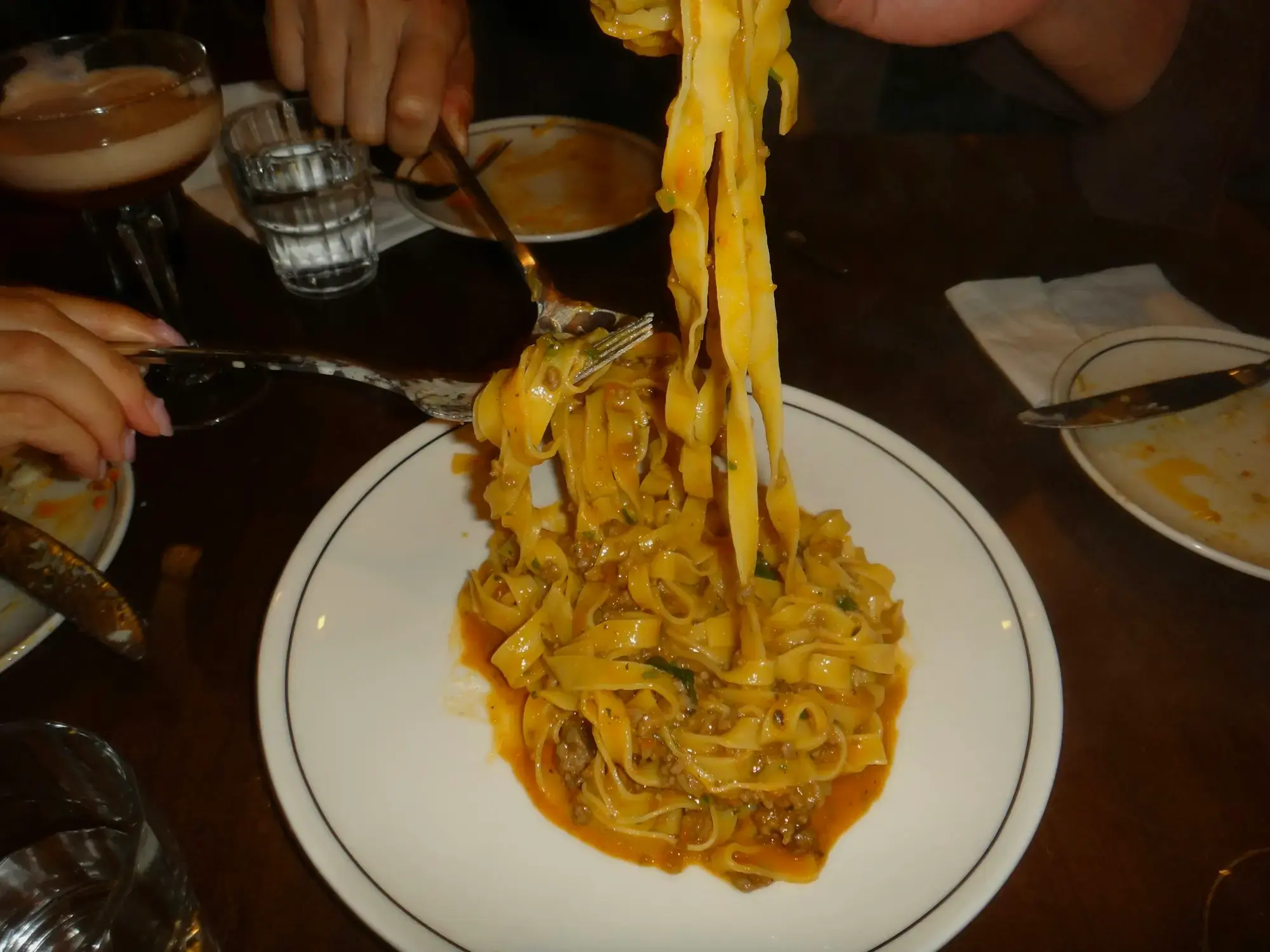 A plate of pasta being lifted with a fork at an Italian restaurant, showing a generous portion