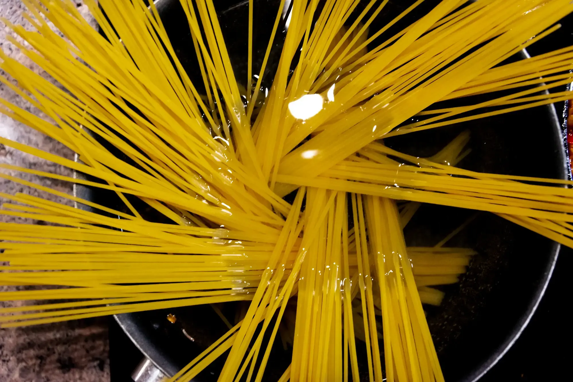 Pasta secca che viene calata in una grande pentola di acqua bollente e ben salata