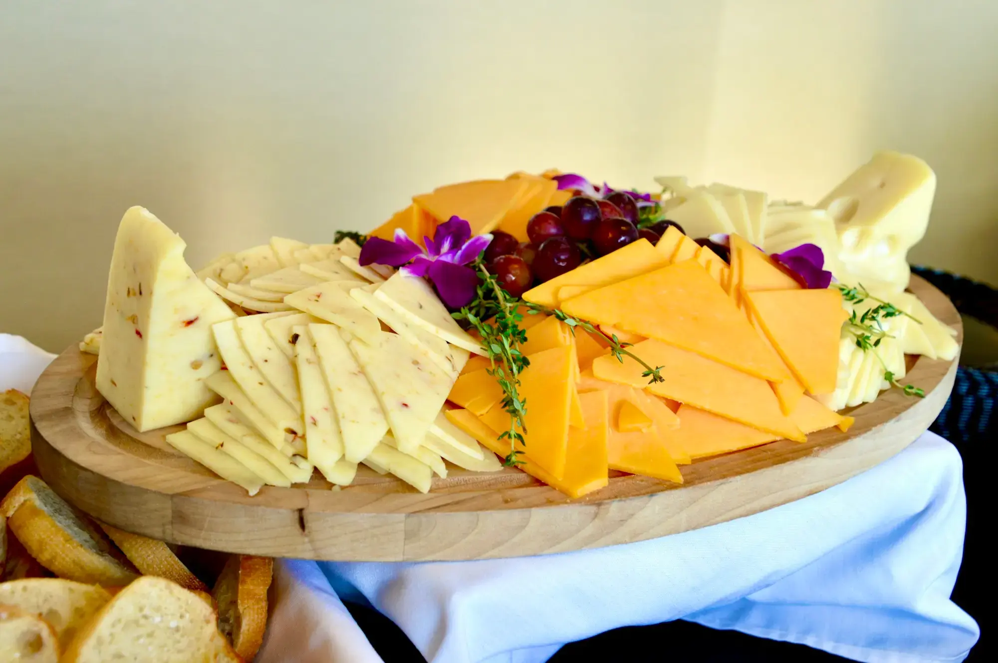 Slices and wedges of different hard and semi-hard cheeses arranged on a wooden cutting board