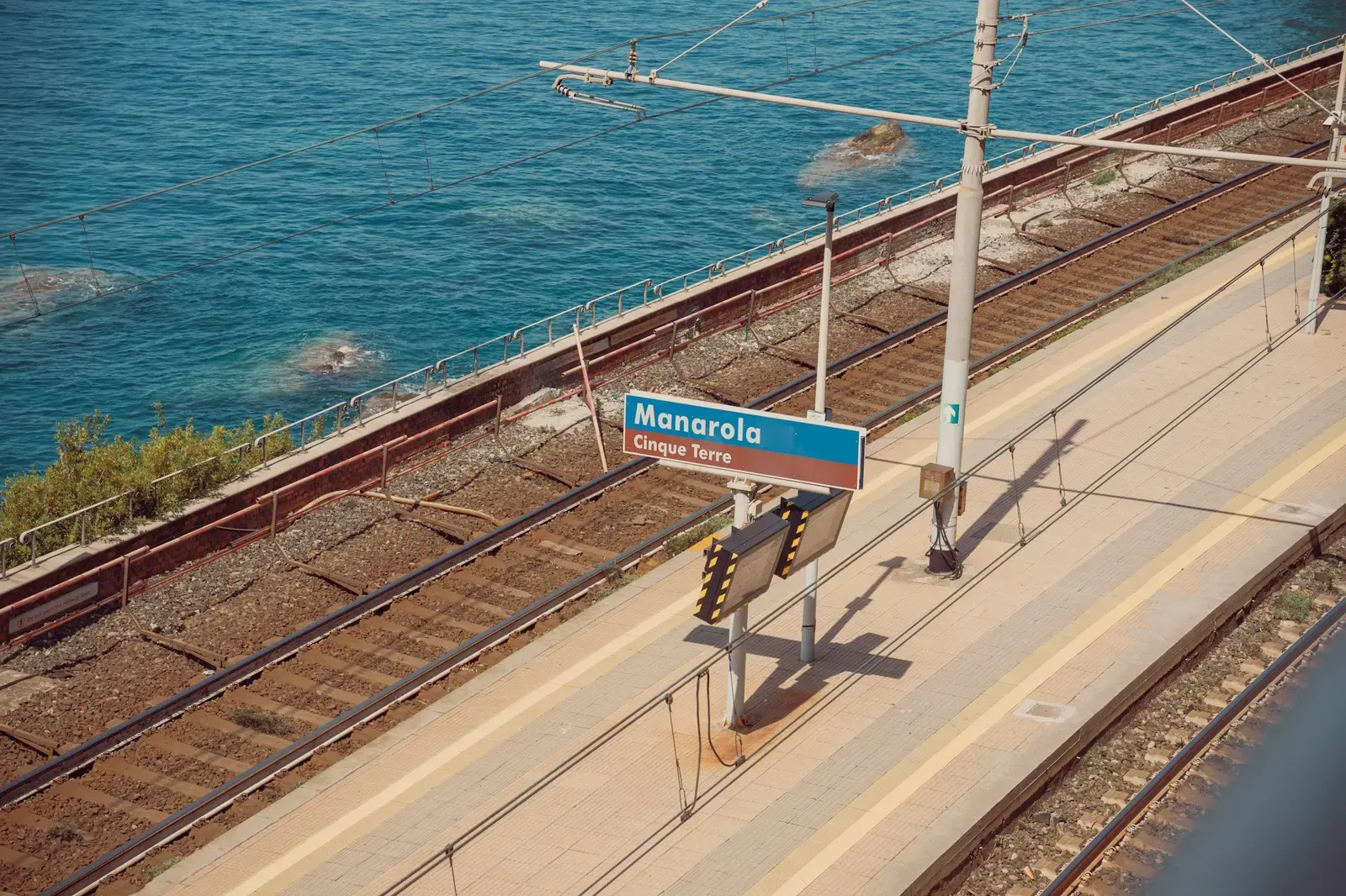The station platform at Manarola in the Cinque Terre, with the station sign and tracks beside the sea